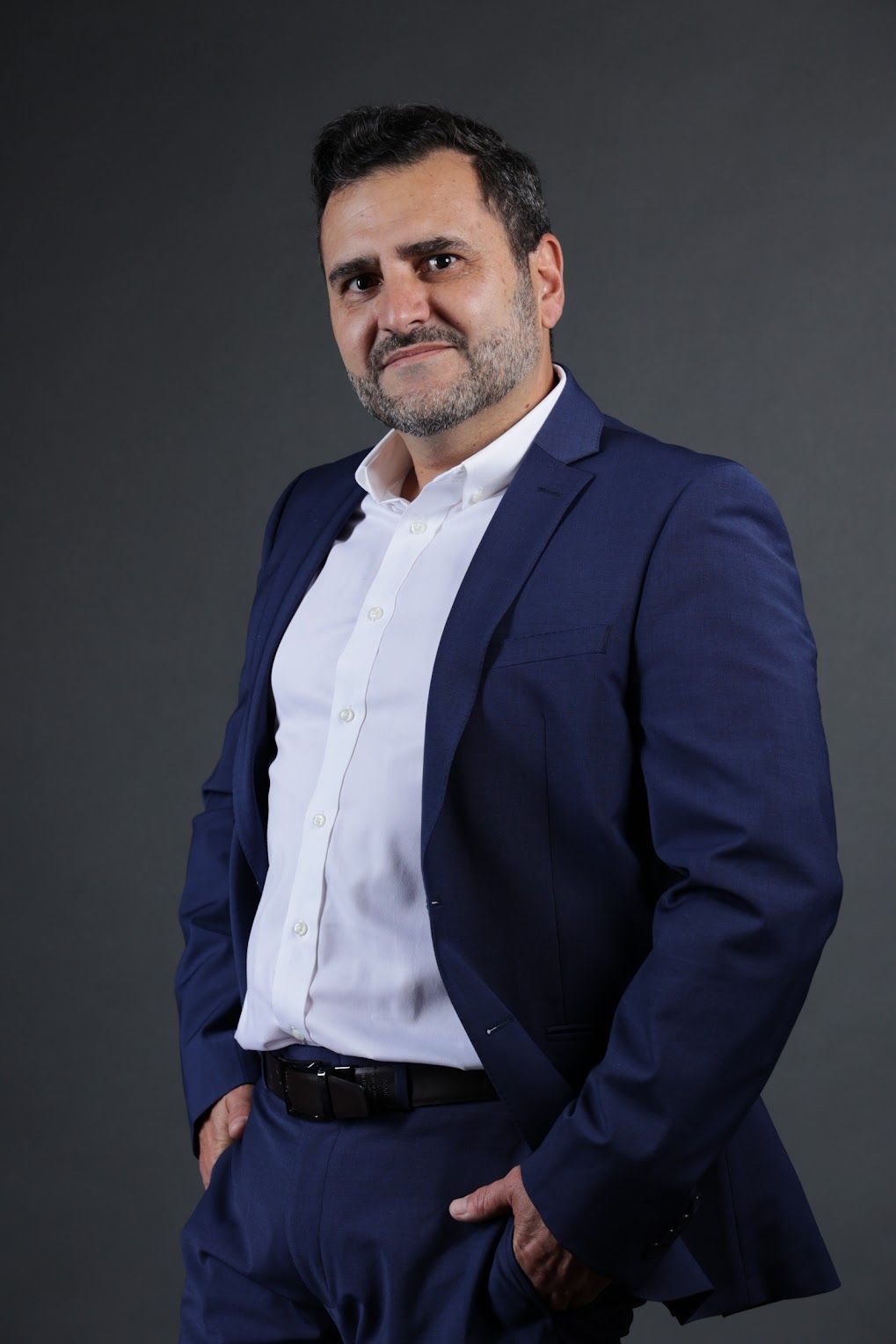 Tino Aguirre, AI CTO, in a navy blazer and white shirt against a dark gray background